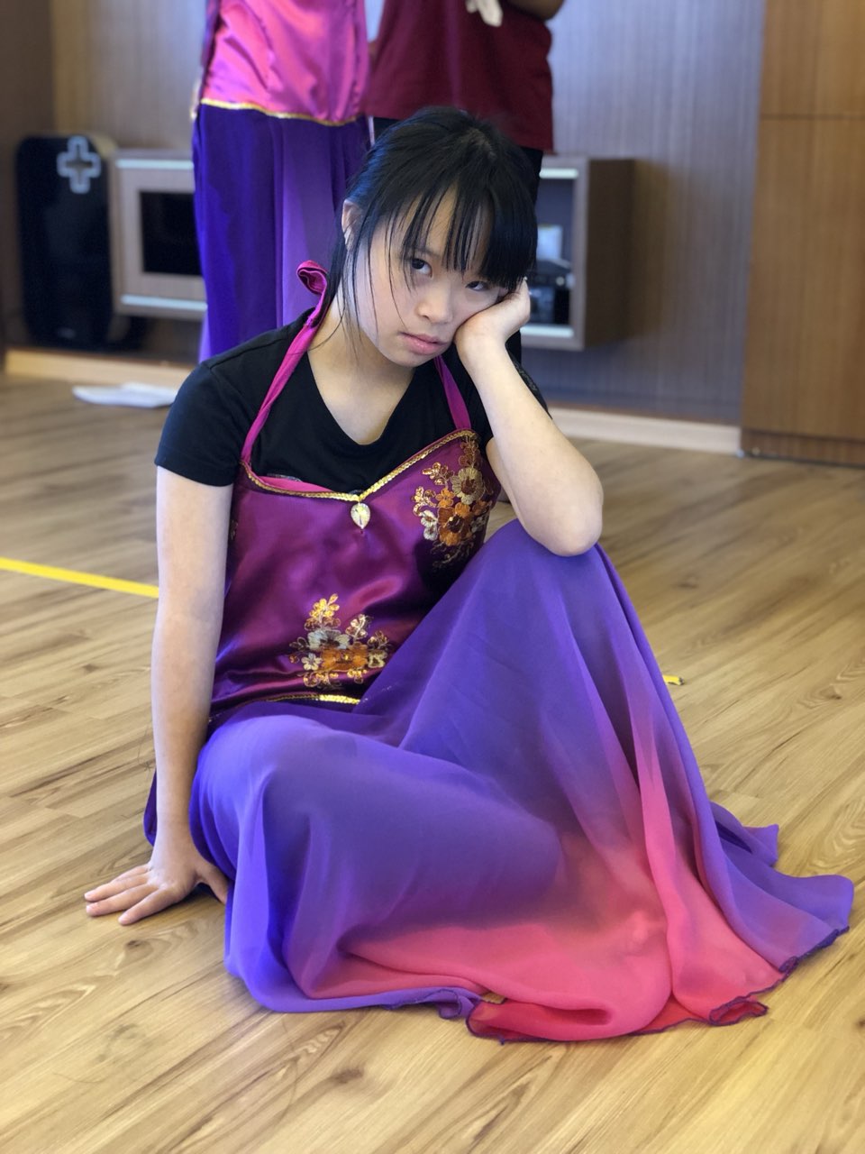 Megan Tang in a purple dance costume, seated in a pose in the studio, 2019