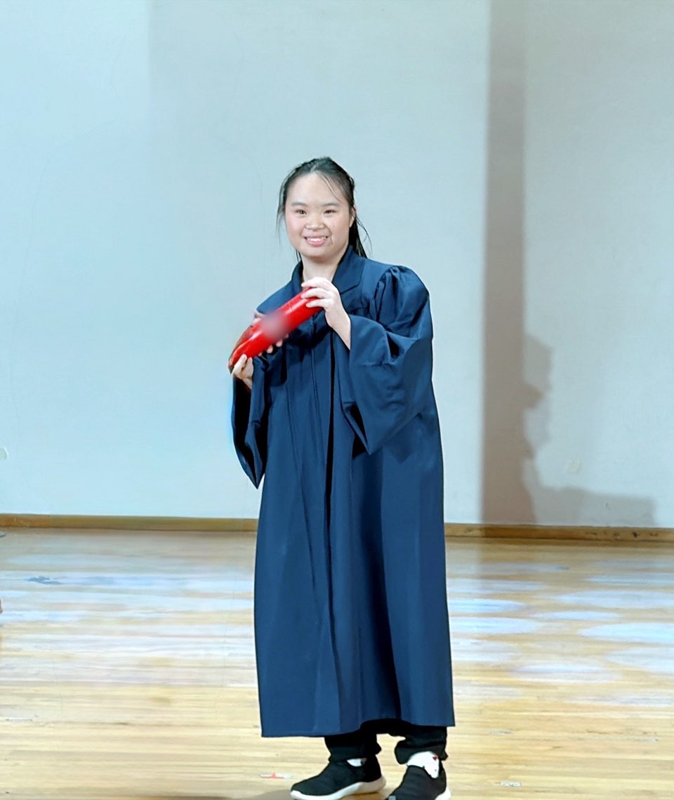Megan Tang on stage in her graduation gown, holding her certificate